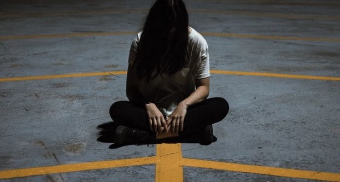 spooky image of girl sitting cross legged on asphalt with her hair covering her face https://unsplash.com/photos/uf12t-rLl2Q