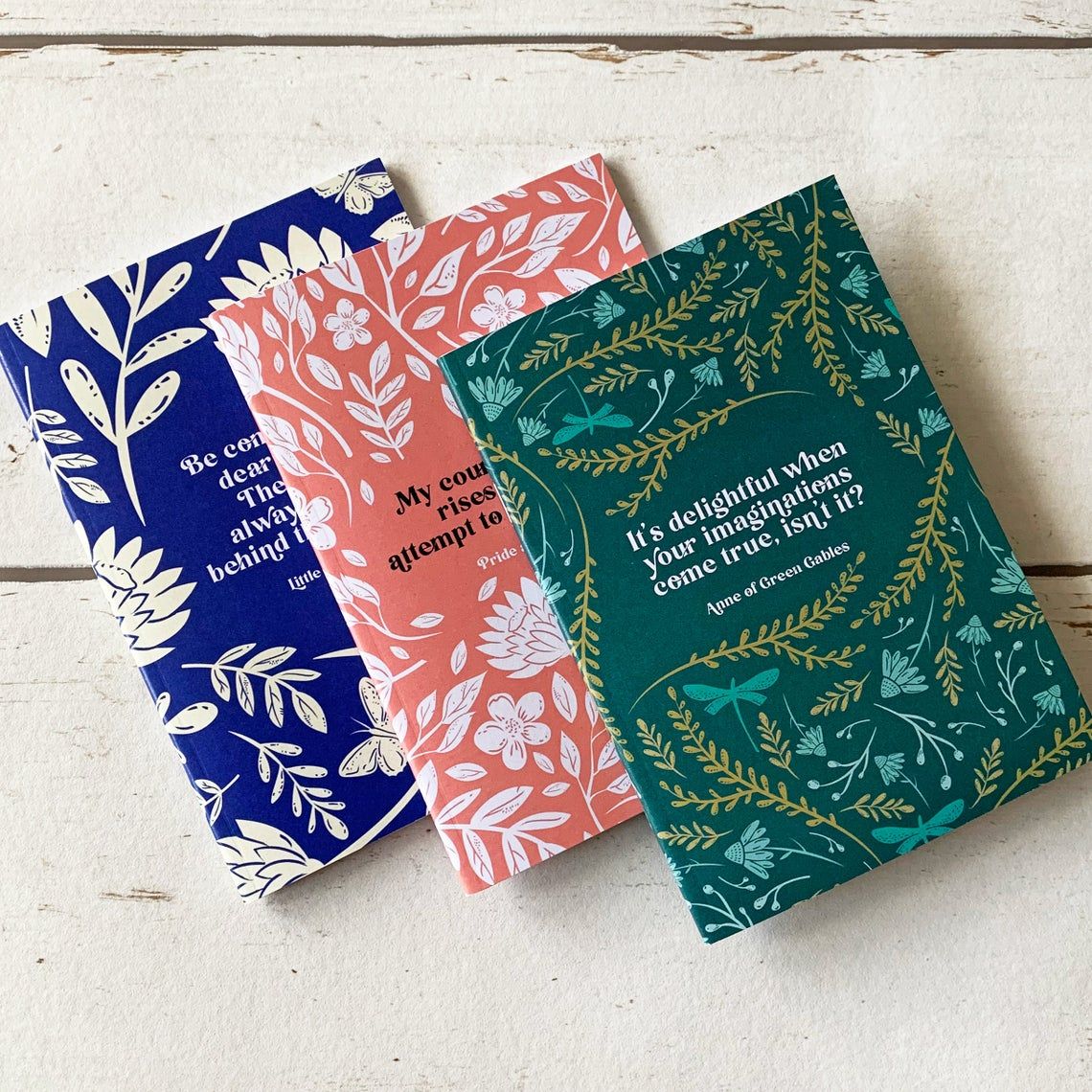 women of literature notebooks, colored blue, red, and green, with quotes from classic heroines