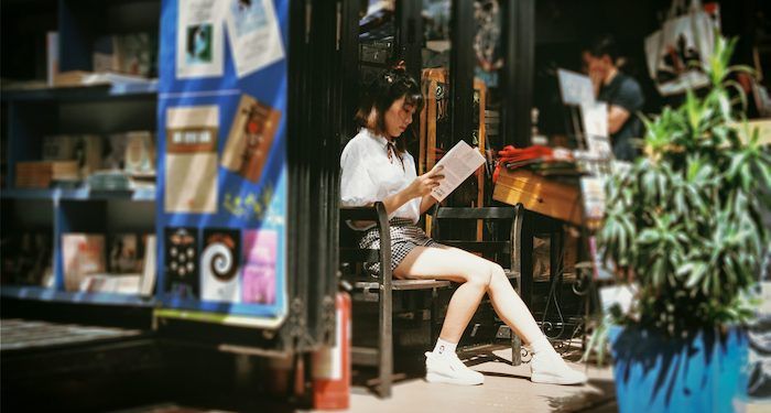 Asian woman reading outside bookstore