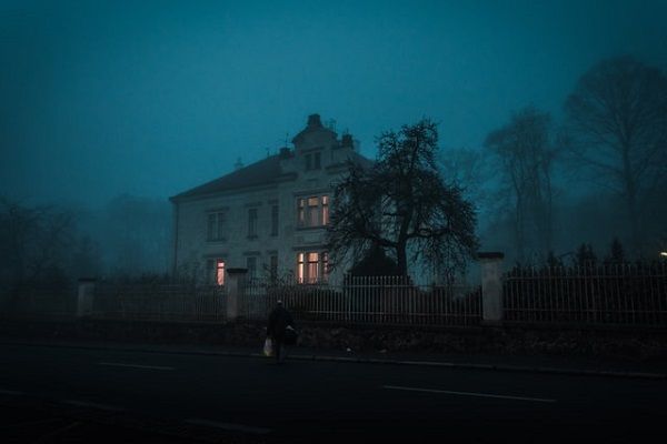 a large house at night surrounded by fog