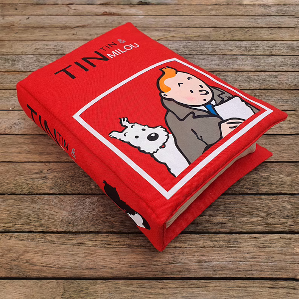 A thick red pillow made to look like a Tintin book with TinTin and Milou on the cover.