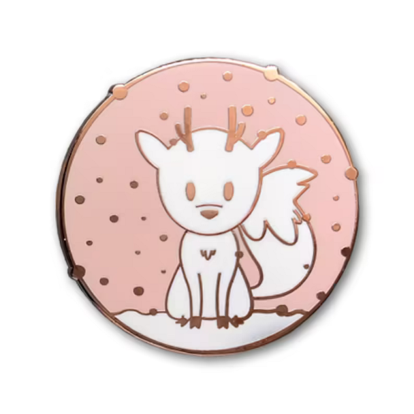 A pink, white, and rose gold enamel pin with Twig the Deerfox sitting in the snow.