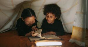 two kids reading in blanket fort