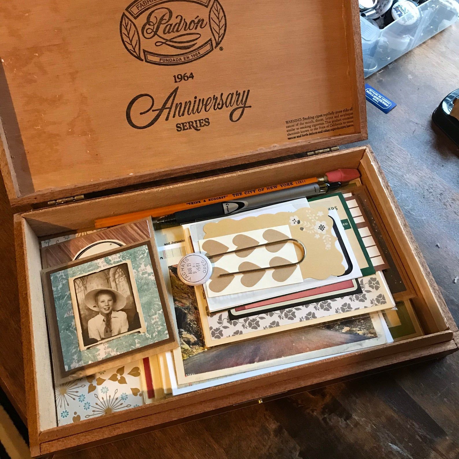 Image of cigar box with vintage style stationary inside, including pencils and pens. 