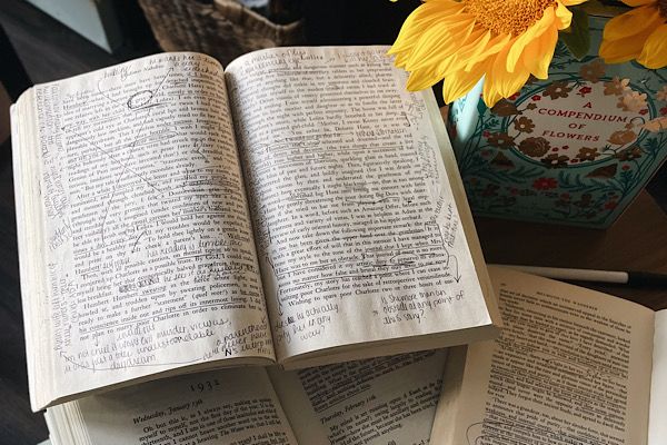 Open, annotated book lying open beside a vase of sunflowers.
Photograph by the author of this piece, Leah von Essen.