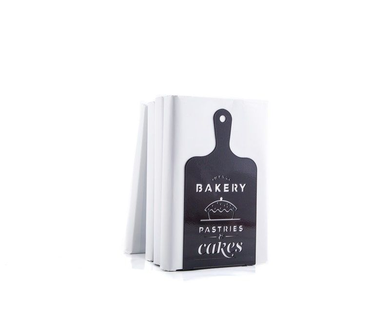 A metal bookend shaped like an old-fashioned cutting board with a long handle. Text on the cutting board says "Bakery Pastries & Cakes" and there's an illustration of a pie.