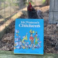 A chicken with the book Mr. Watson's Chickens