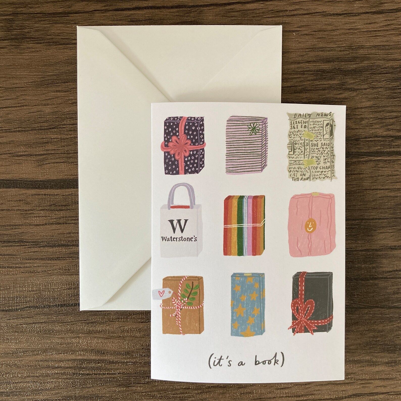 A card with a bunch of wrapped packages in various types of wrapping paper, and words that read "it's a book"