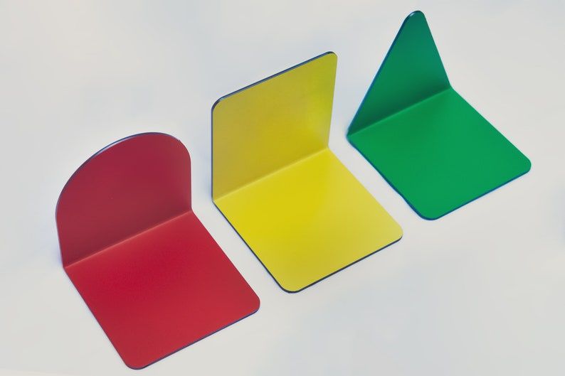 Three bright metal bookends: a red half circle, a yellow square, and a green triangle.