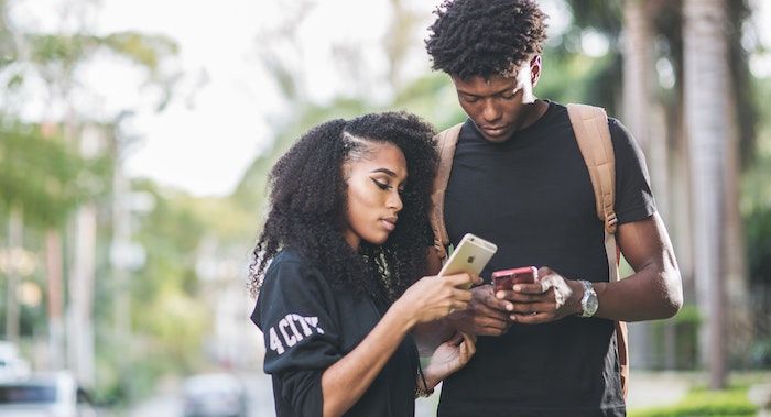 Image of two Black teens looking at their phones