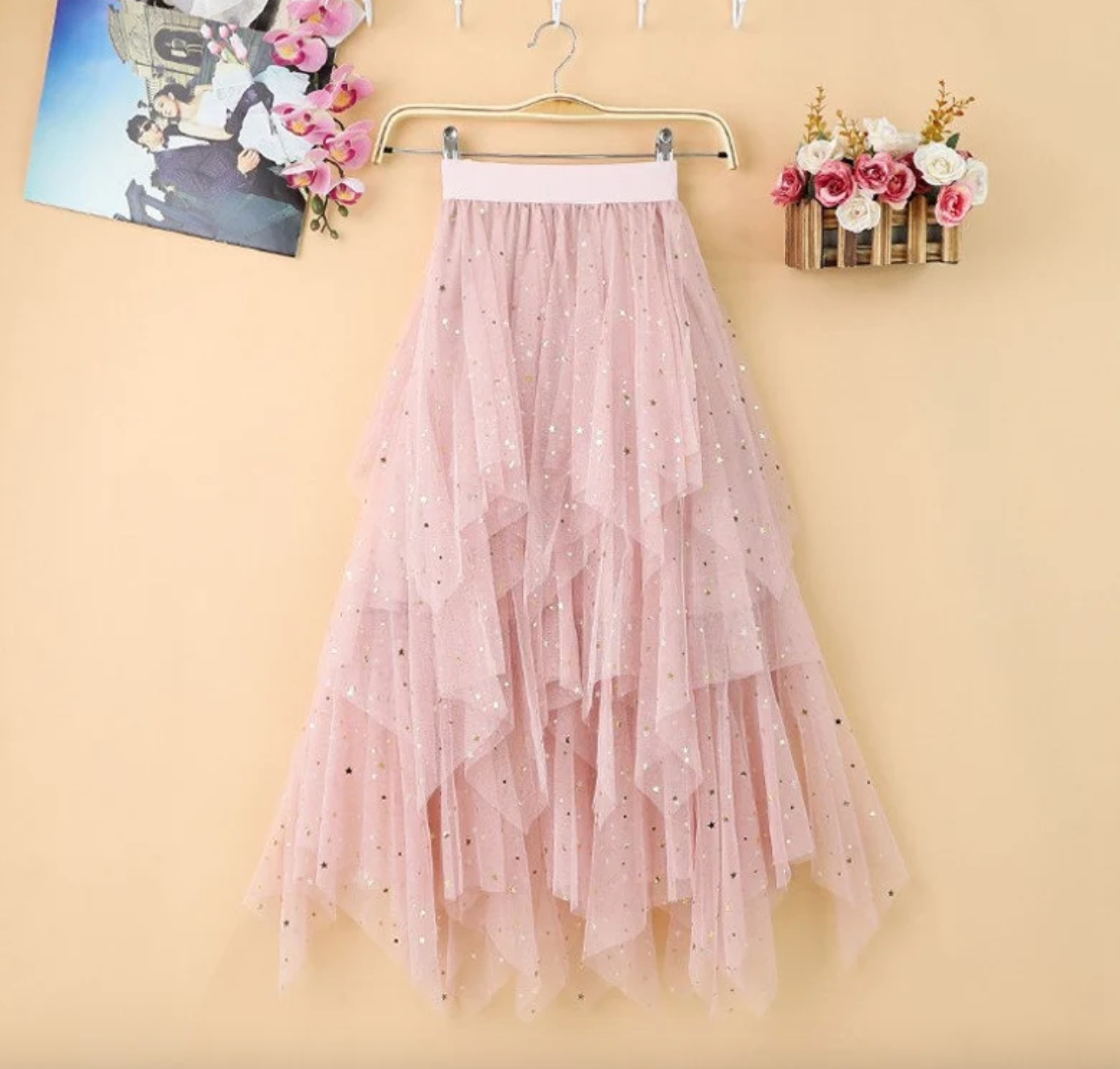 Layered pink tulle skirt with glitter hanging on wall next to photo and flowers