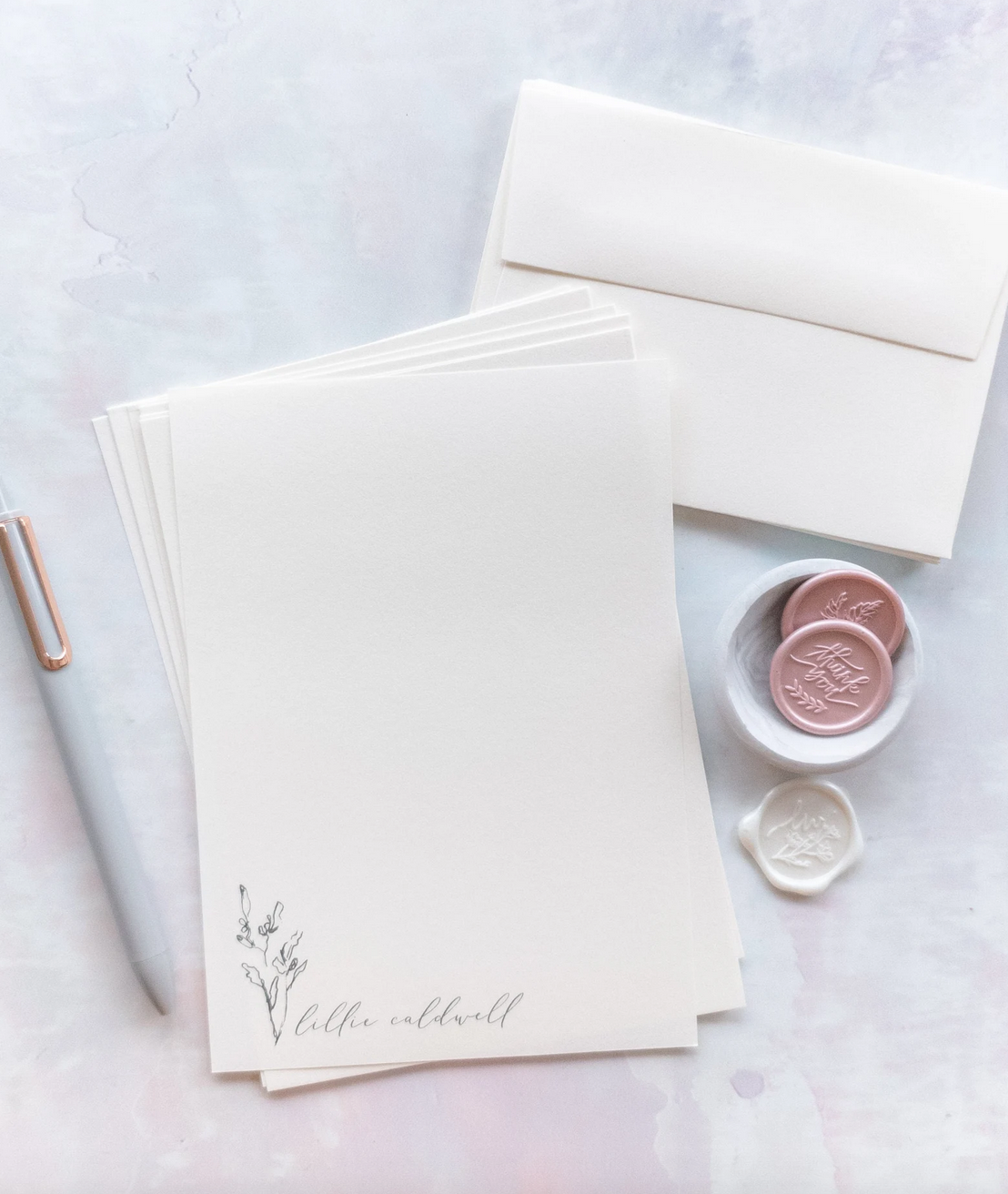 Cream colored stationary with white pen and pink and white wax buttons