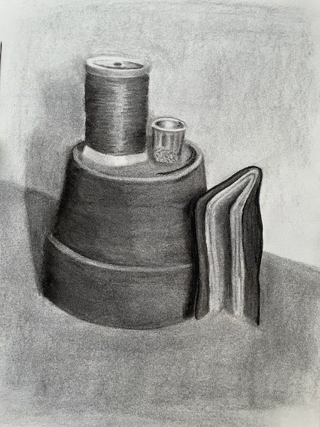 A charcoal still life drawing of an upside-down plant pot with a thimble and a bobbin of thread sitting on top. Next to the pot is a small, soft cover notebook.