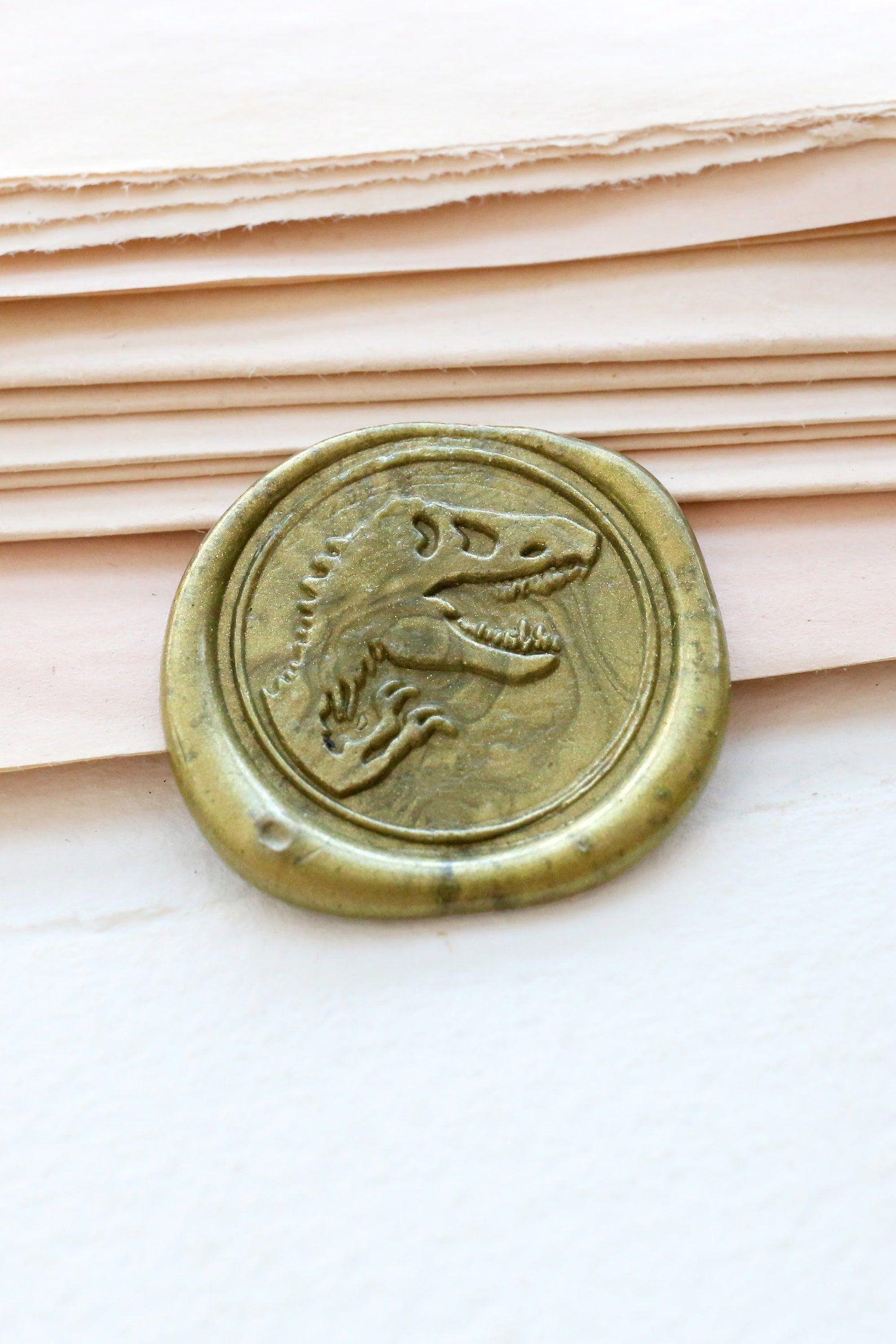 Image of a gold wax seal featuring a dinosaur.