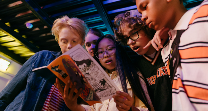 a group of young people staring open-mouthed at a comic book