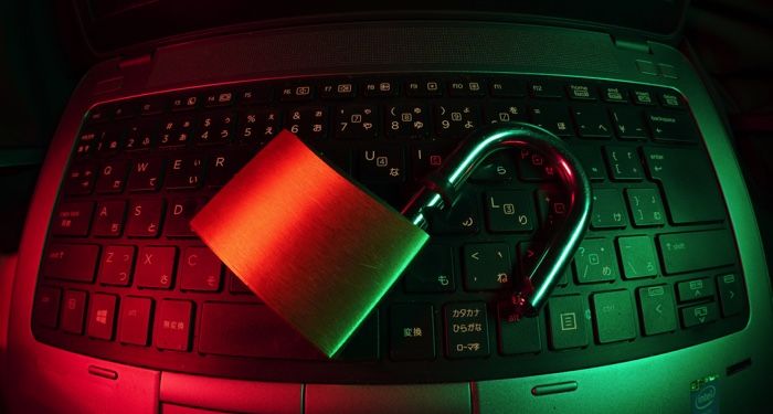 a padlock resting on a laptop keyboard, image is bathed in red and green light