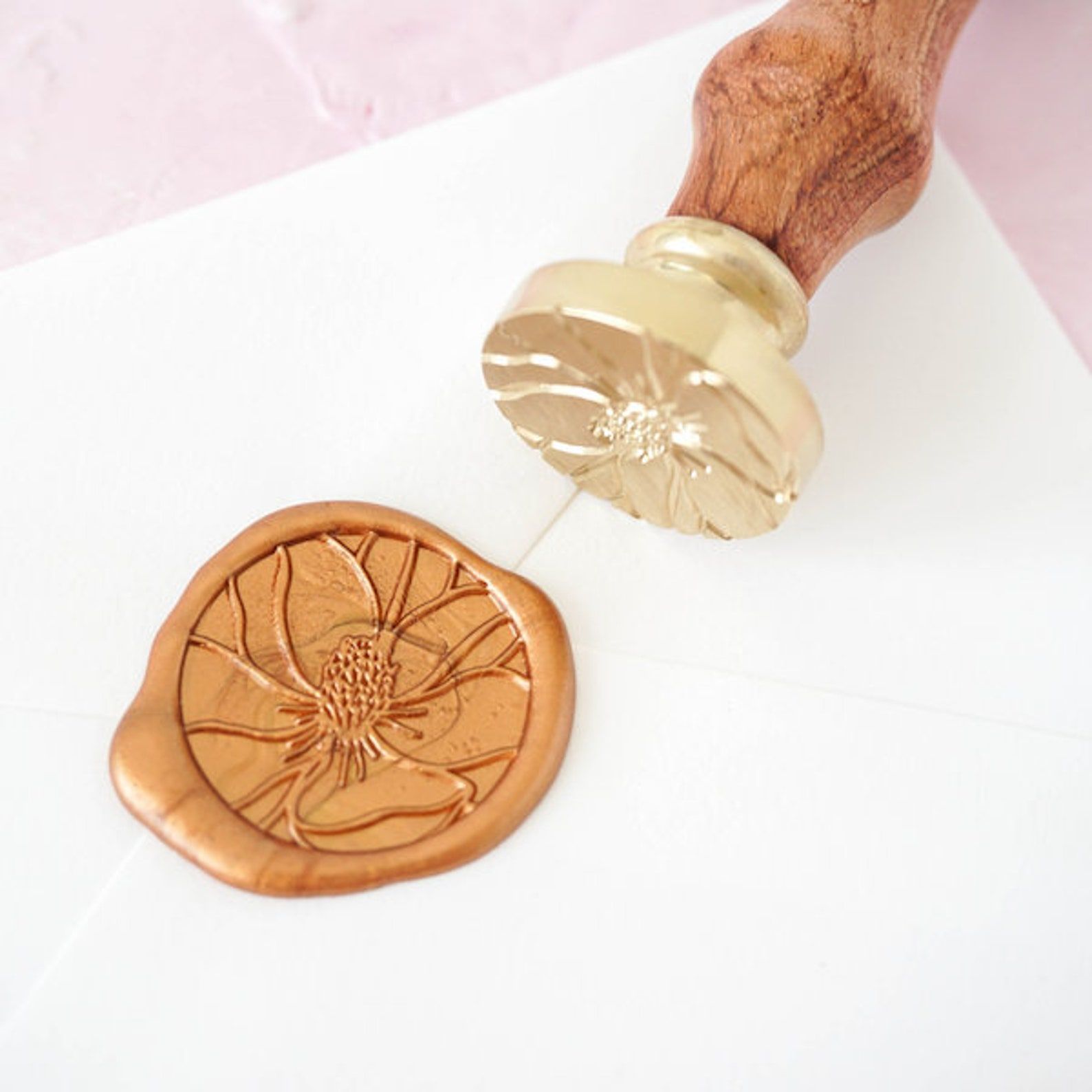 Image of a wax seal stamper and stamp, which is in the shape of a magnolia flower. 