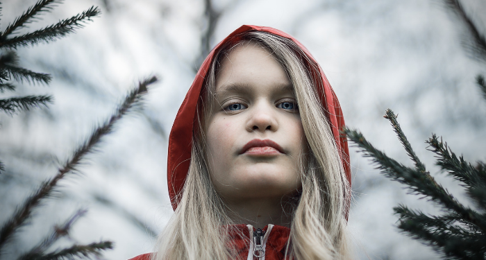a girl in a red and white hoodie surrounded by tree branches