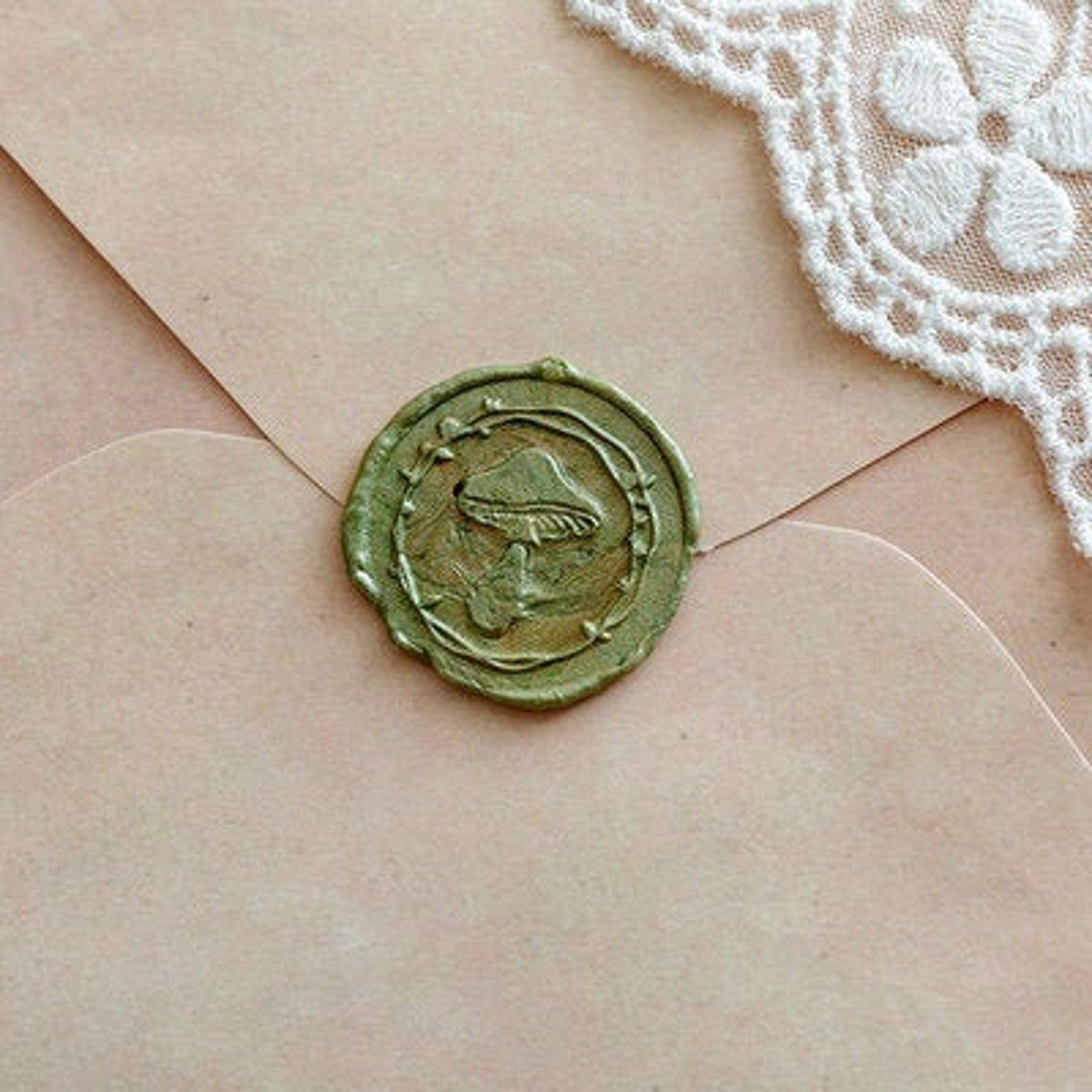 Image of a green wax seal on a manilla envelope. The stamp features a big mushroom. 