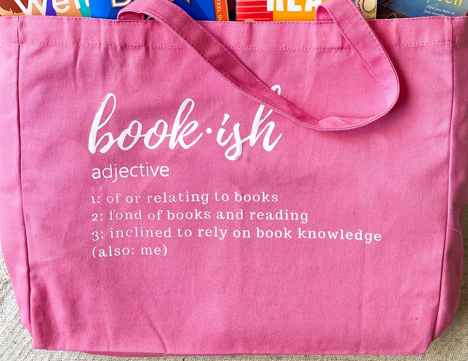 Big pink tote bag with white lettering. 