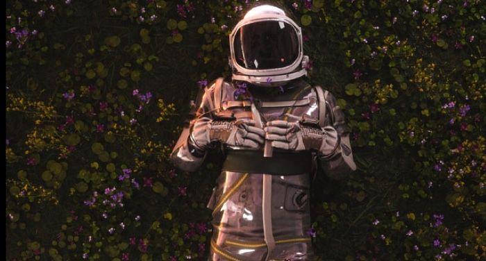 person in a space suit in a field of flowers