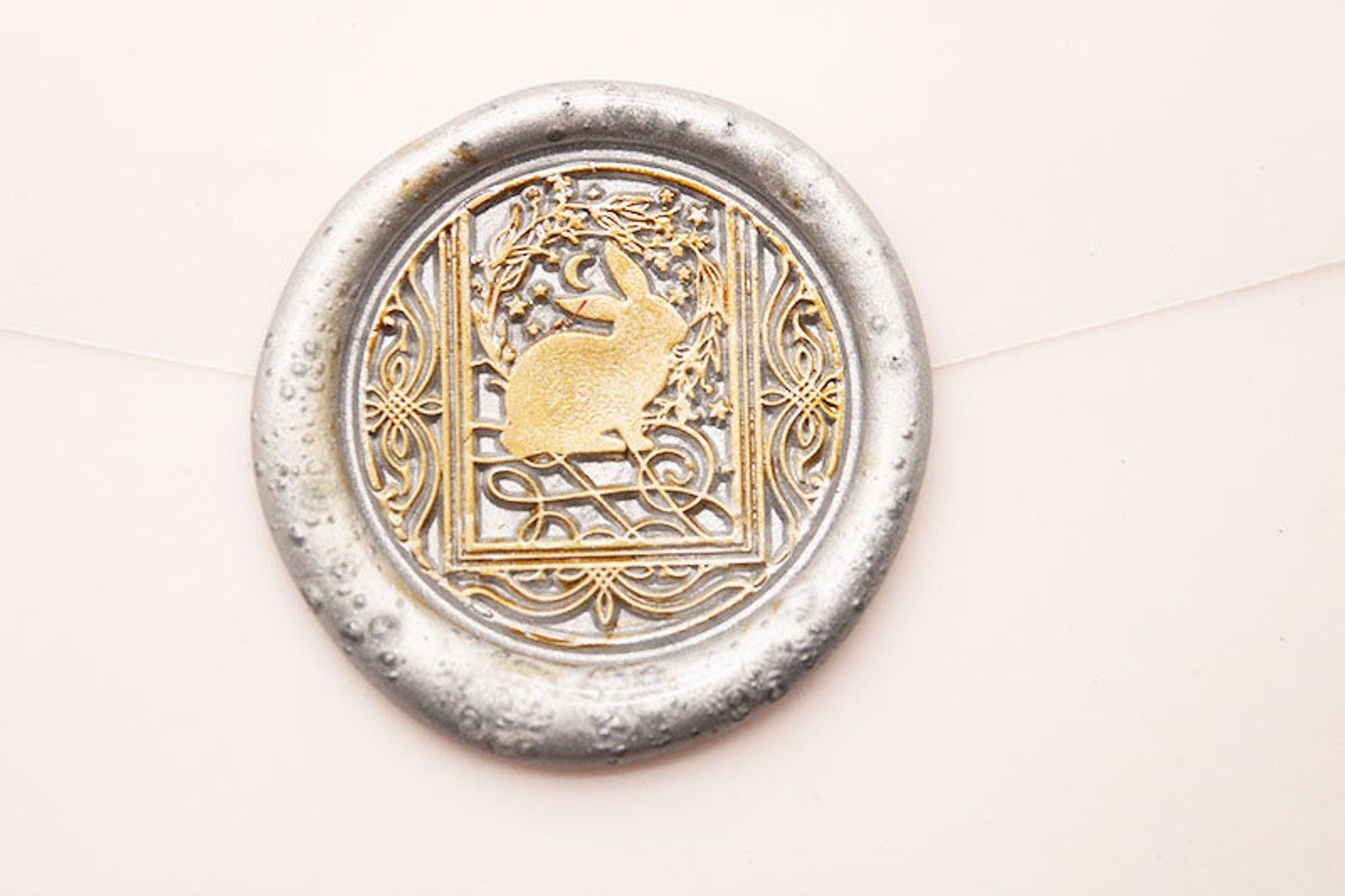 Image of a silver wax seal stamp. It is gold inside with an image of a rabbit inside a tarot card. 