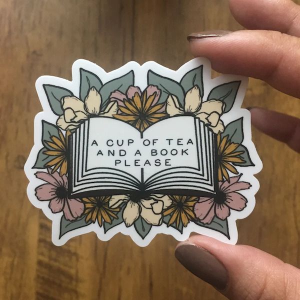 sticker featuring an open book reading "a cup of tea and a book please"