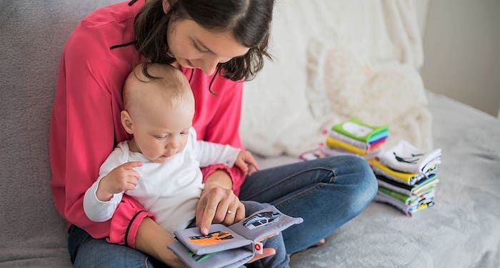 a photo of a woman reading a cloth book to a baby