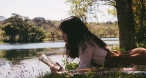 a young Asian woman reading by a pond
