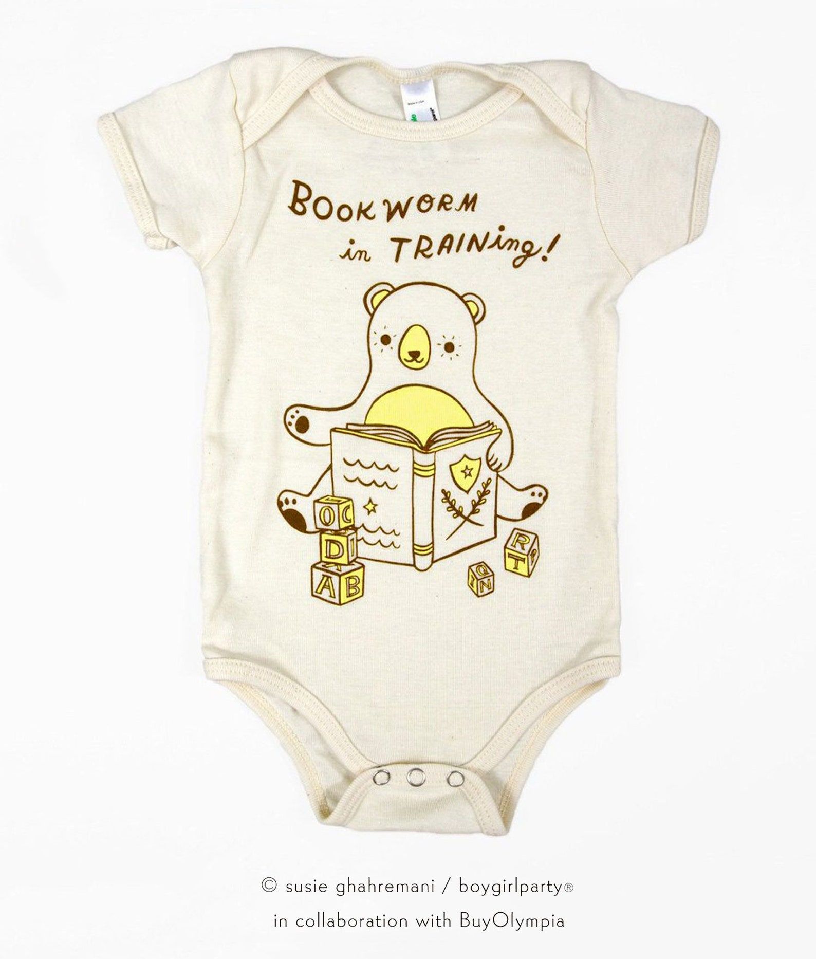 Image of a cream-color bodysuit for babies. In the center is a bear with blocks and it reads "bookworm in training."