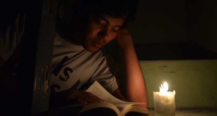 a person reading a book by candlelight