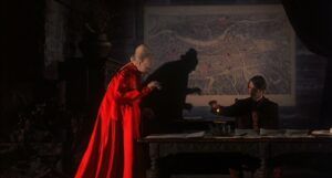 still from 1992 Bram Stoker's Dracula showing Dracula and Keanu Reeve's character at a table; Dracula is hunching over creepily