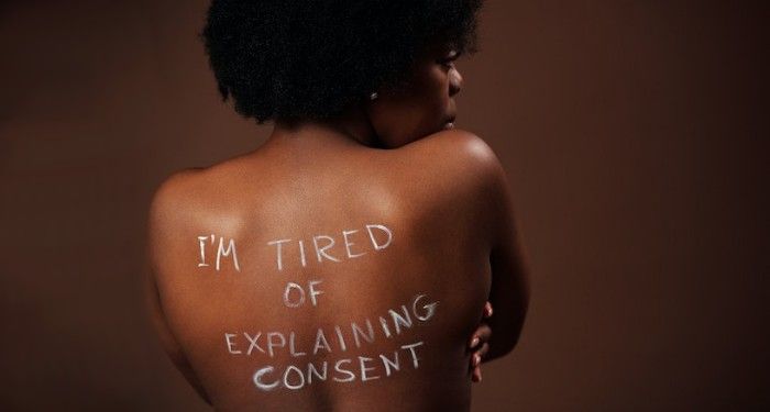 Black woman with her back to the camera and I'm tired of explaining consent written on her back