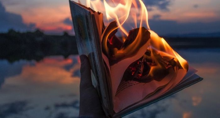 a hand holding a burning book