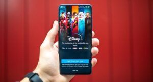 image of a white hand holding a phone with an open disney+ app