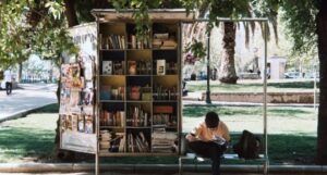 young man sitting on a bench and reading in front of a book stand