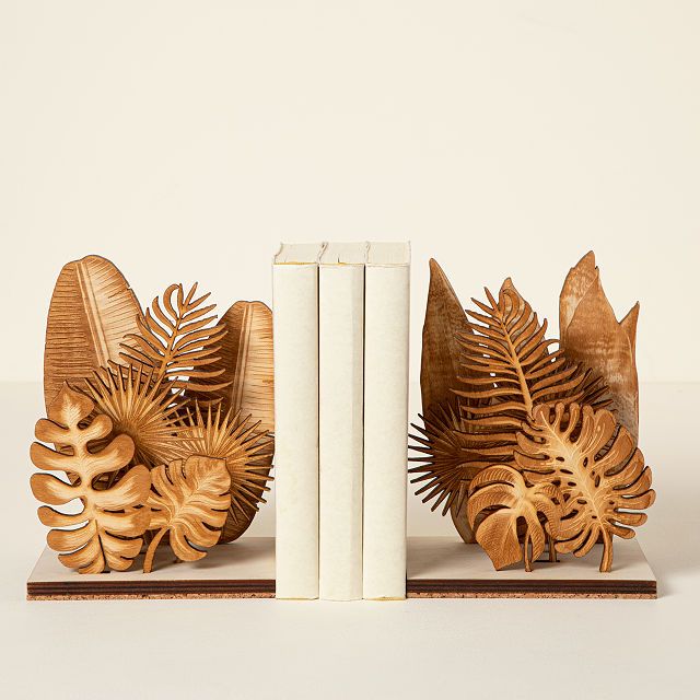 Image of a set of bookends. They're wooden and feature all kinds of houseplant leaves. 