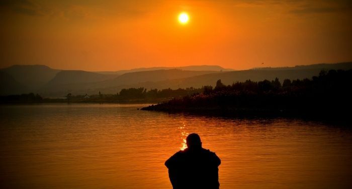 Image of a person sitting in front of a setting sun