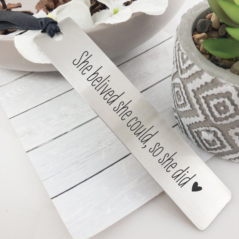 Image of a silver metal bookmark which reads "She believed she could, so she did <3". 