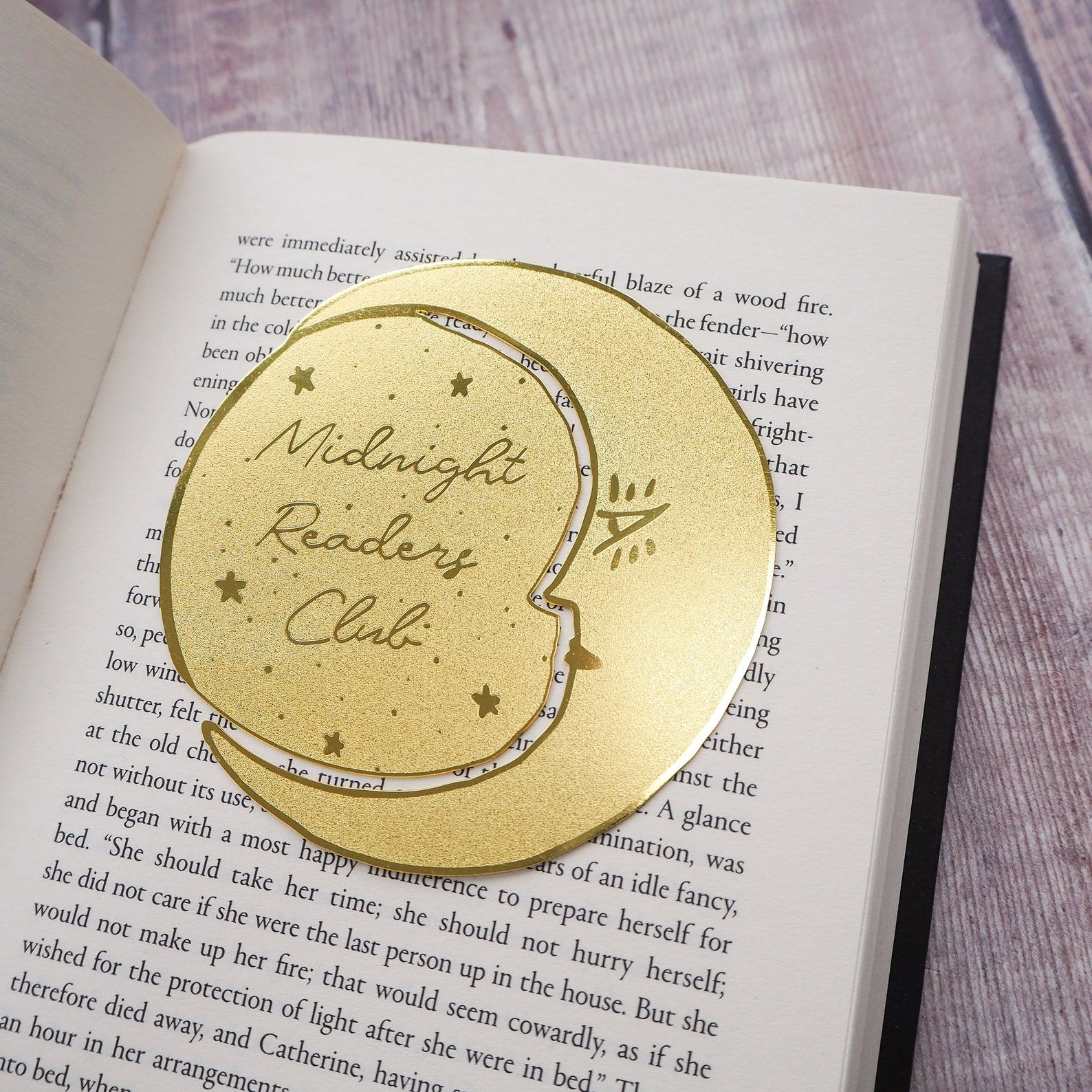 Image of a round metal moon bookmark, which reads "Midnight readers club."  
