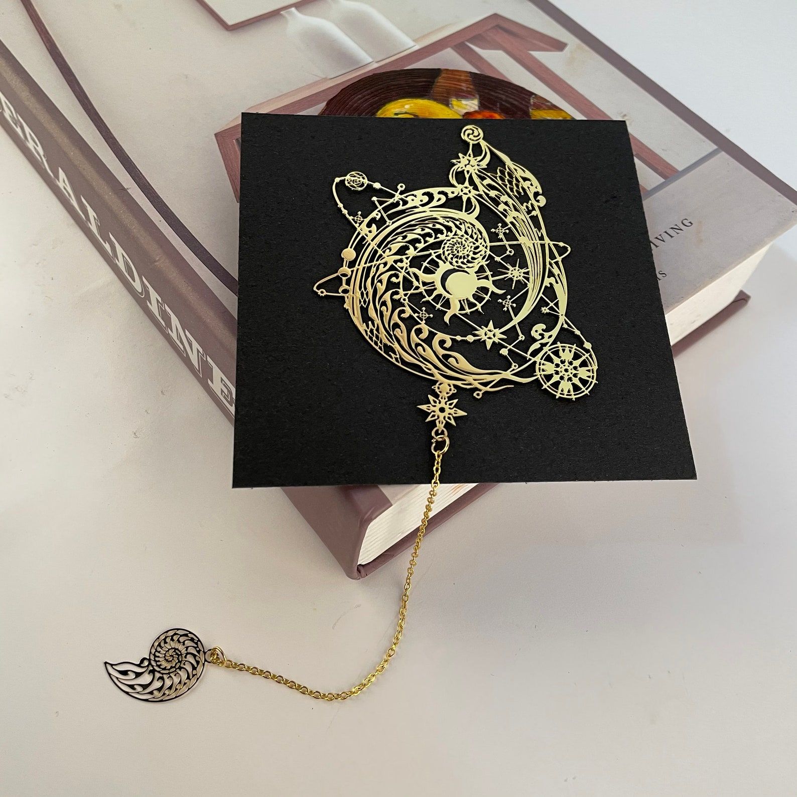 Image of a gold bookmark designed like  a globe. It's on a black book cover. 