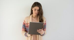 a photo of a white woman reading on a tablet