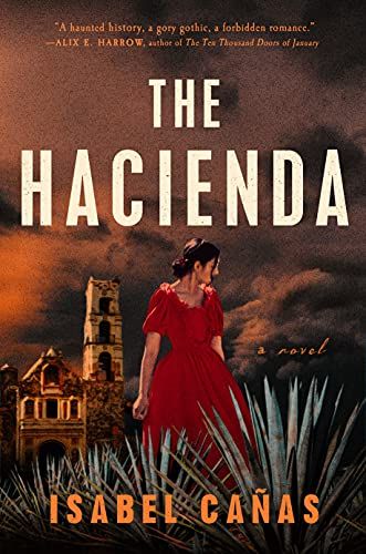 cover of The Hacienda by Isabel Cañas, with a photo of a woman with dark hair in a red dress standing in tall grass in front of a crumbling estate under ominous skies