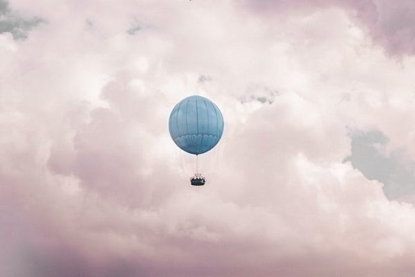 a photo of a blue hot air balloon against a pink cloudy sky