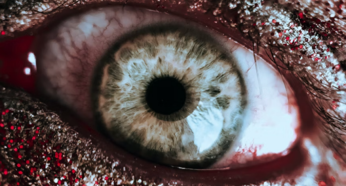 bloody eye close-up surrounded by red and silver glitter; photo by Perchek Industrie for unsplash