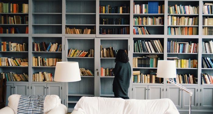 woman looks at shelves full of books in a residence
