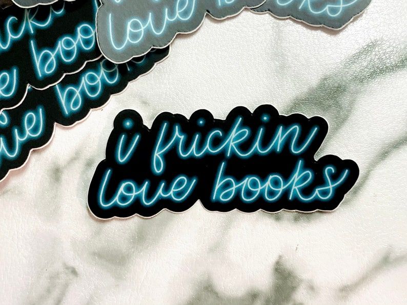 Black sticker with electric blue writing. The writing reads "i frickin love books."