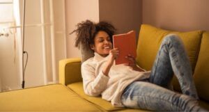 image of a Black woman reading on a yellow couch