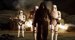 Adam Driver as Kylo Ren flanked by threee Stormtroopers in a still frame from Star Wars Episode VII: The Force Awakens