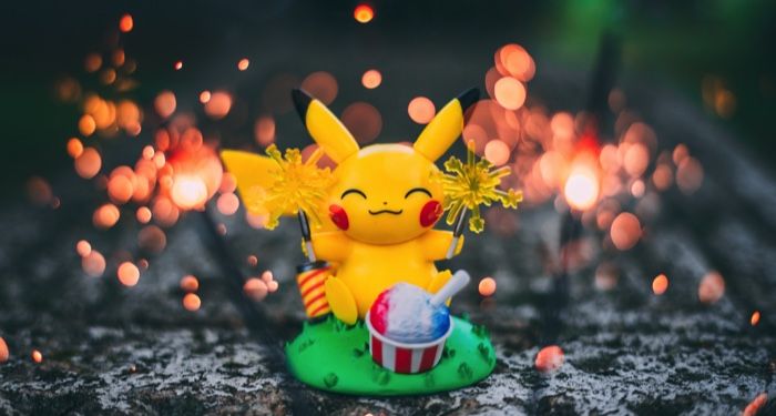 a Pikachu figurine with a poke ball and fireworks